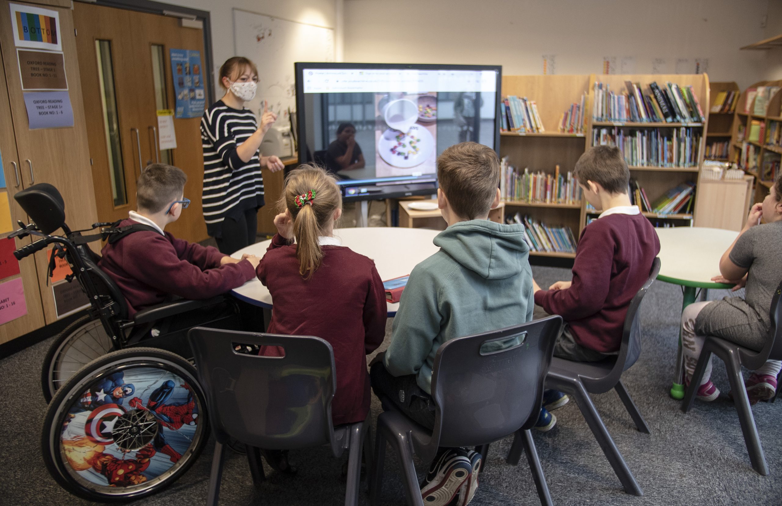 SEND learners in the class room with their teacher watching a video on a screen